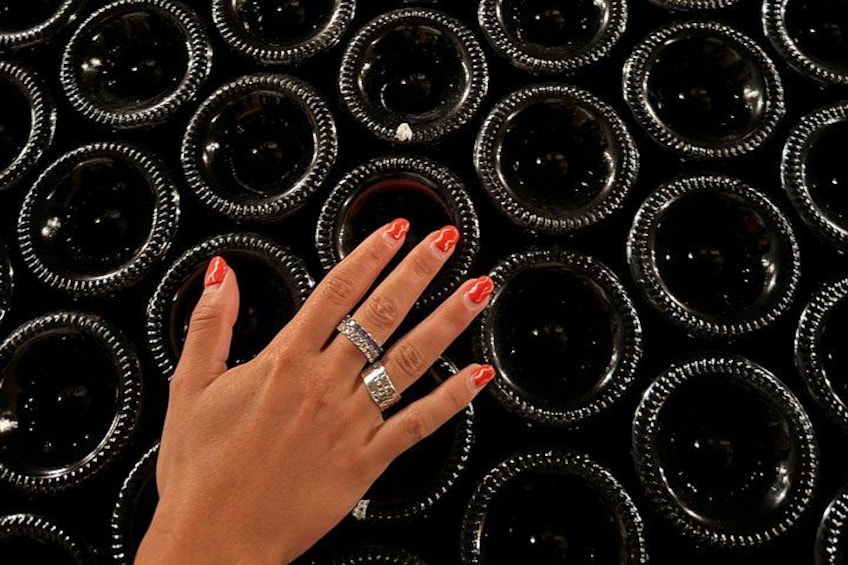 Una mano con lo smalto rosso e un anello che sfiora diversi oggetti circolari neri. 5