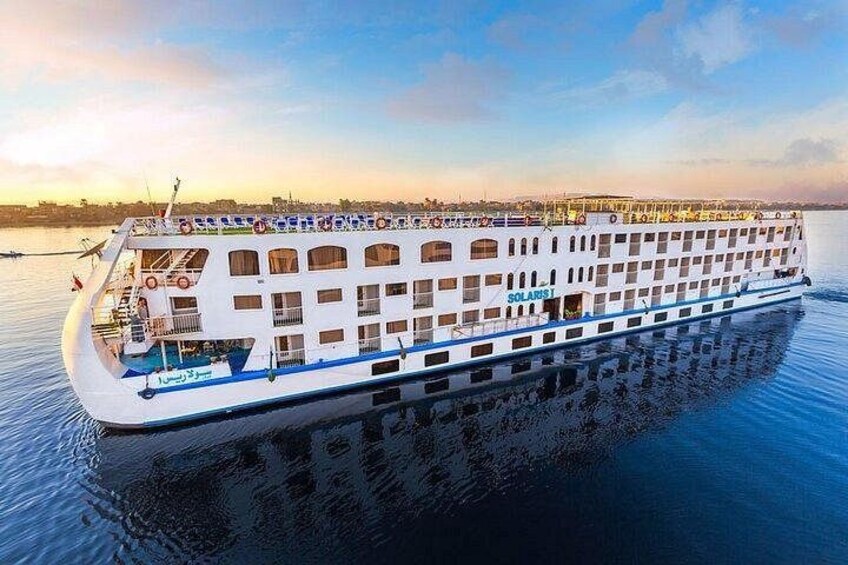 A large white cruise ship with multiple decks and windows, floating on calm water. 1