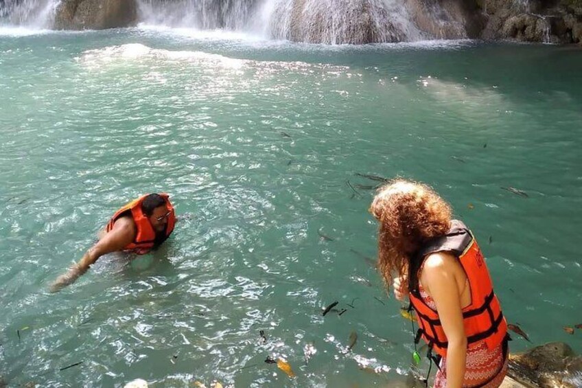 Two people in a body of water with a waterfall in the background. 2