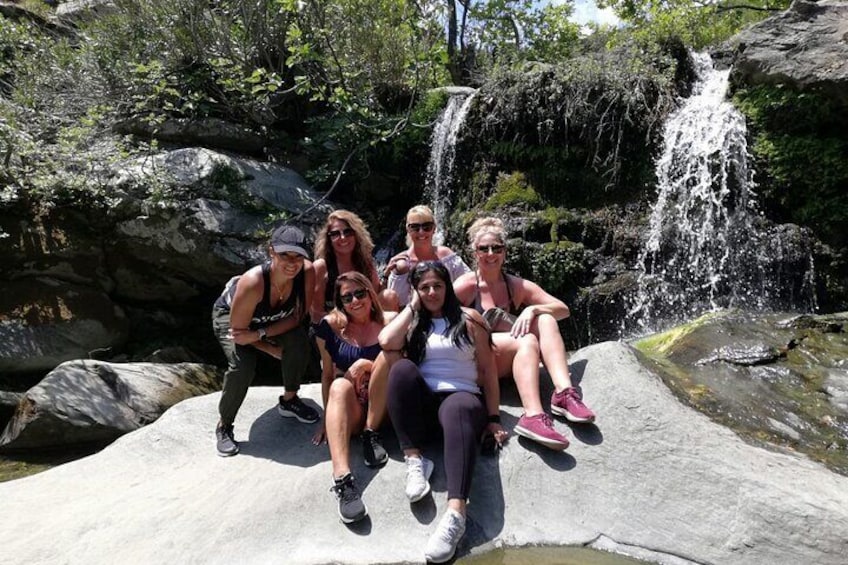 A group of people sitting on a rock with a waterfall in the background. 4
