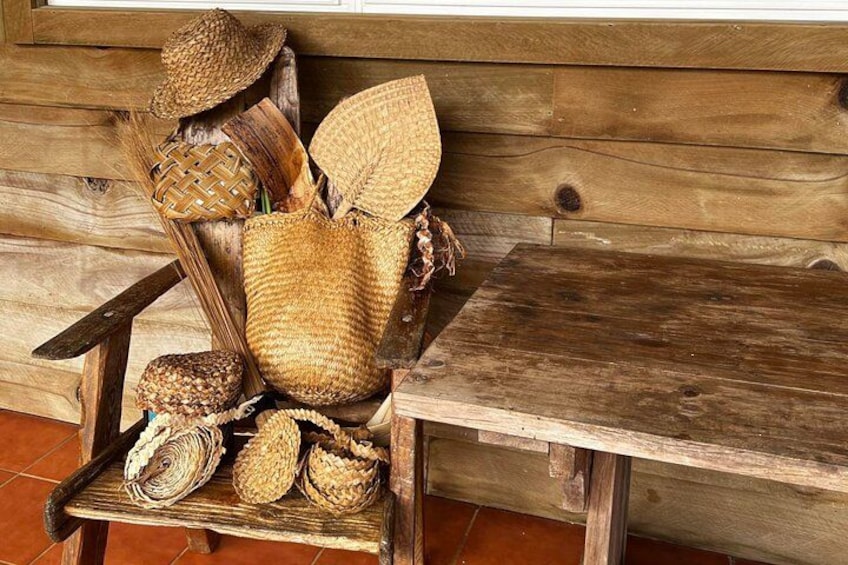 A rustic wooden bench with woven baskets and hats. 1