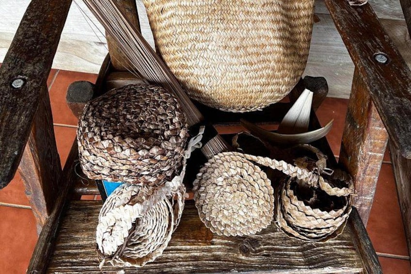 A wooden chair with woven baskets and a woven bag. 3
