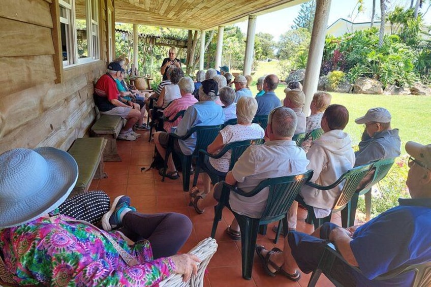 A group of people seated outdoors on chairs, facing a speaker. 2
