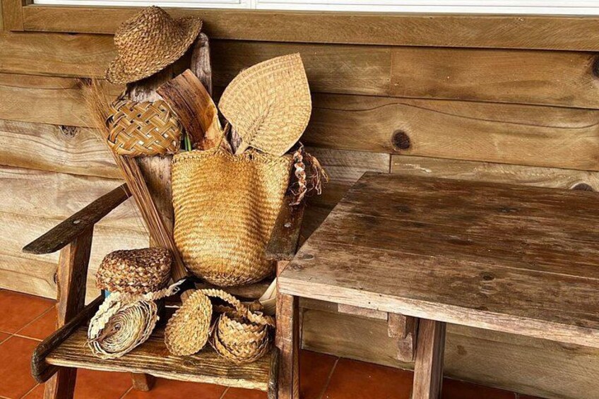 A rustic wooden bench with woven baskets and woven hats. 2