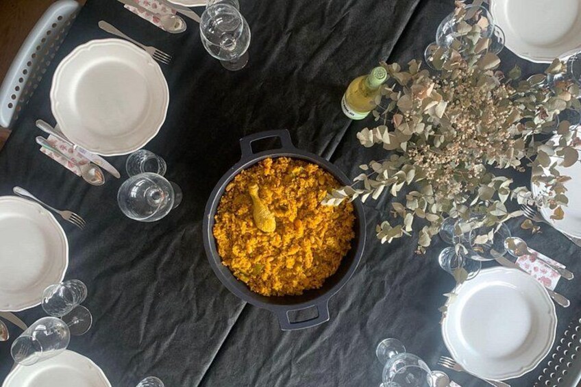 A table set for a meal with a pot of food in the center, surrounded by plates, cutlery, and glasses. 2