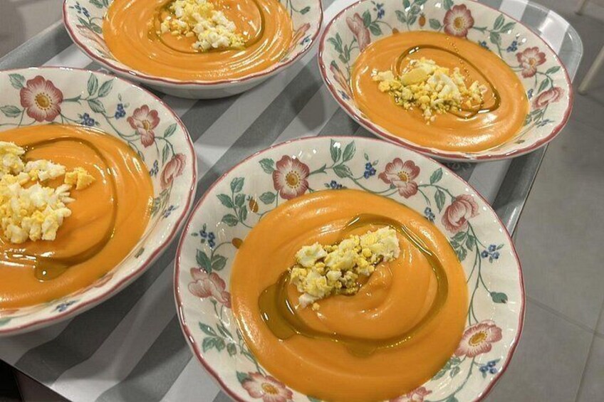 Tres tazones de sopa de naranja con un toque de crema y pan tostado sobre una mesa. 5