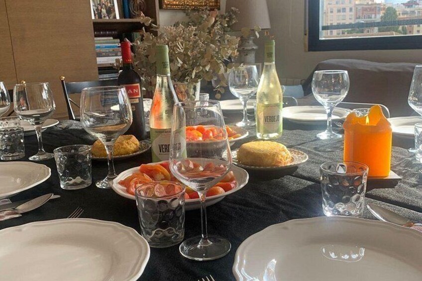 Una mesa servida para una comida, con platos, vasos y botellas de vino. 4