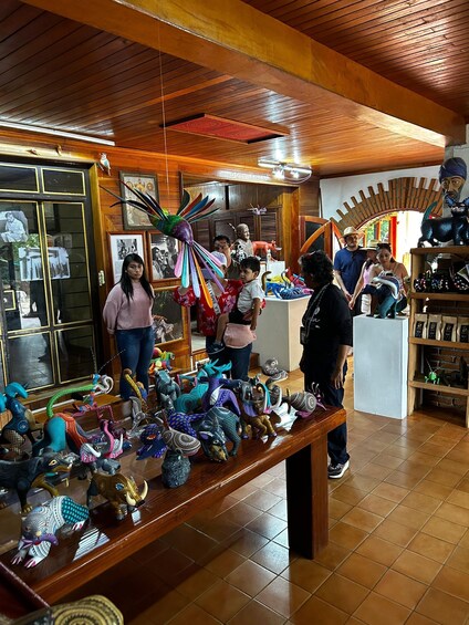 A wooden interior with a display of colorful, intricately designed animal figurines on a table. 2
