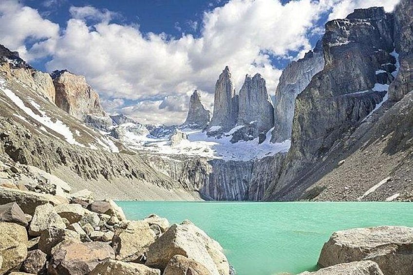 A mountain landscape with a turquoise lake, rocky terrain, and snow-capped peaks. 1