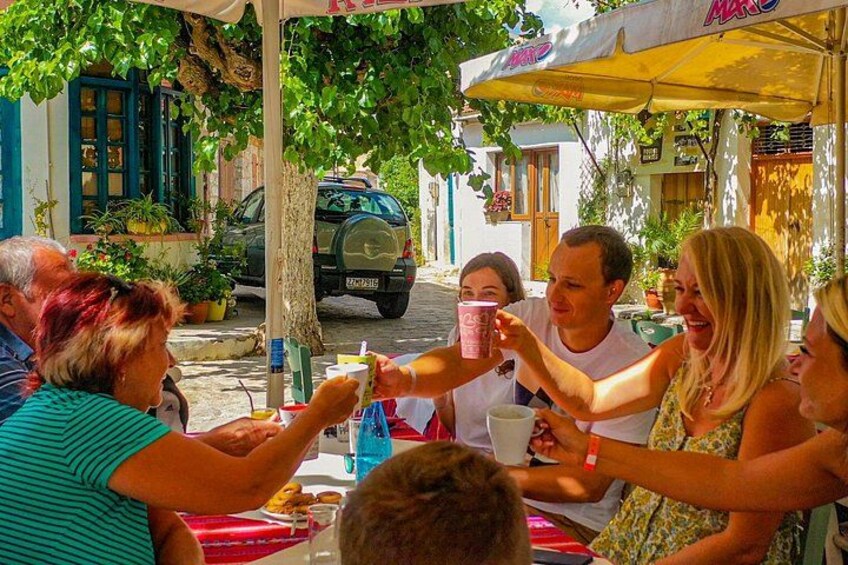 A group of people toasting with drinks at an outdoor café with umbrellas. 4