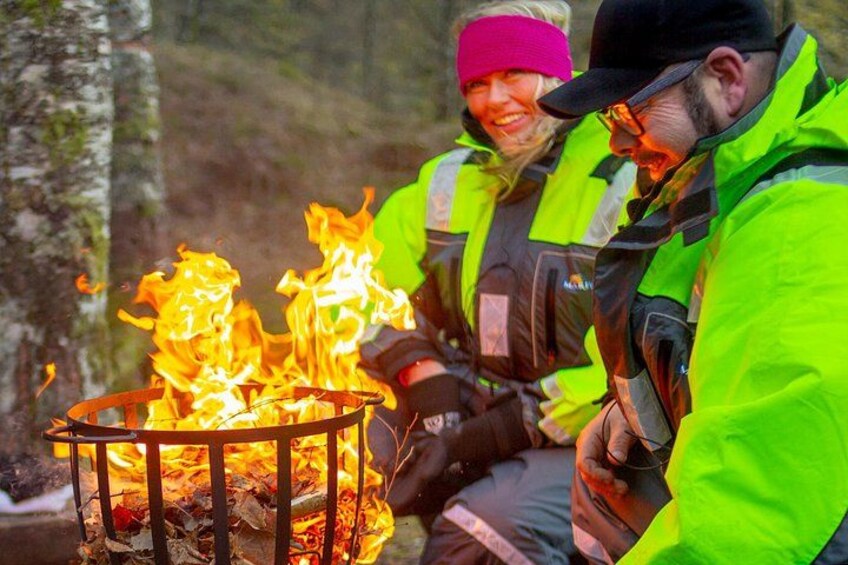 Two people sitting by a campfire in a forest. 5