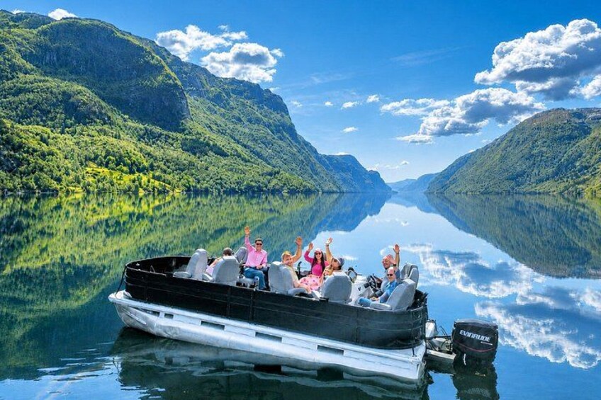 En båd med mennesker på en rolig sø omgivet af bjerge. 1