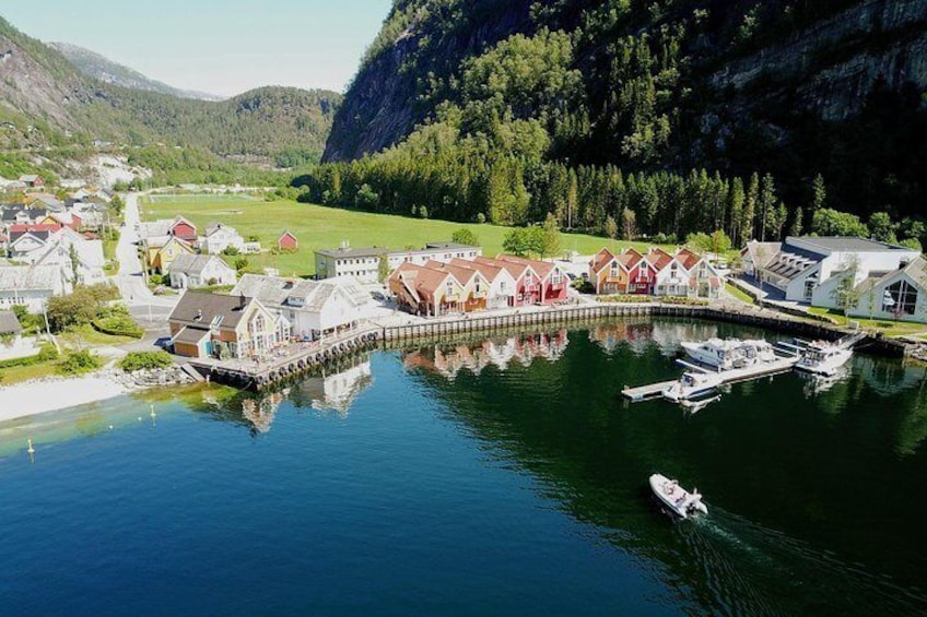 En kustby med hus, en brygga och båtar på stilla vatten. 3