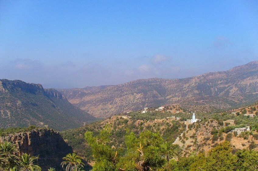 A mountainous landscape with a white building, palm trees, and a valley. 4