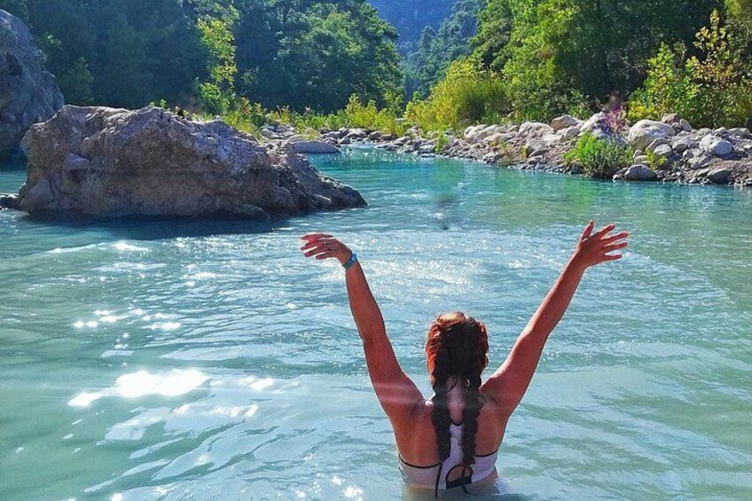 A person in a natural setting with a river, rocks, and greenery. 1
