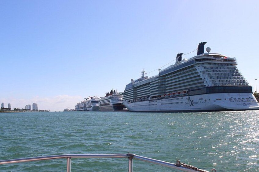 Een groot cruiseschip ligt afgemeerd in een haven, met andere schepen op de achtergrond. 2
