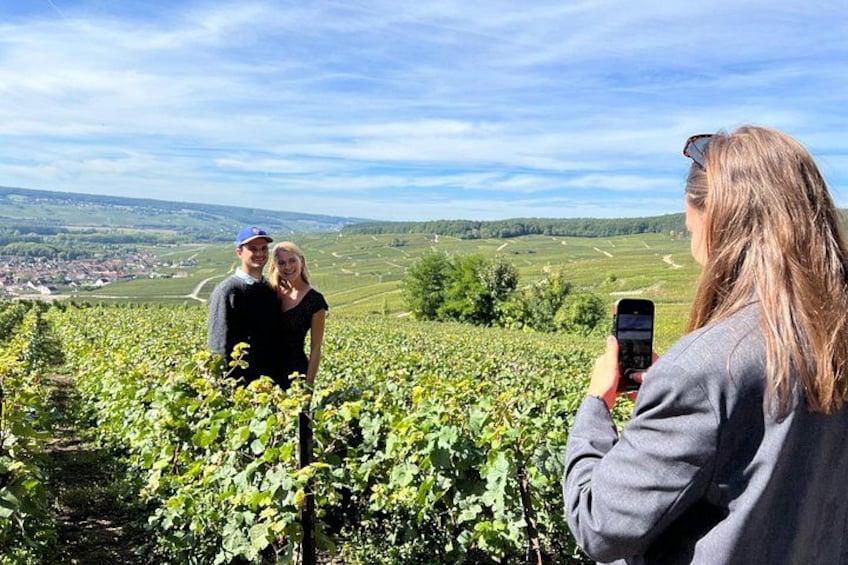 Un vigneto con file di vigna, una persona che scatta una foto e una vista panoramica di un paese in lontananza. 4