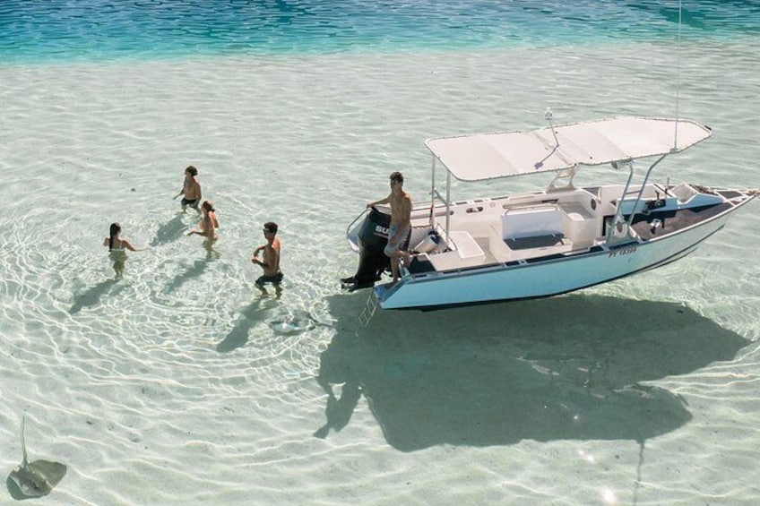 Een boot met mensen op een zandstrand bij helder water. 2