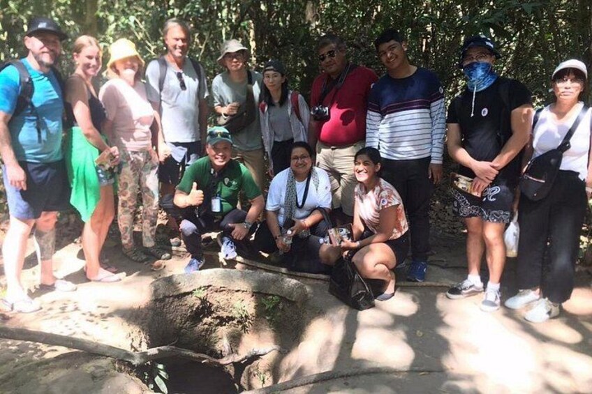 A group of people posing in a natural setting with trees and a rock formation. 4
