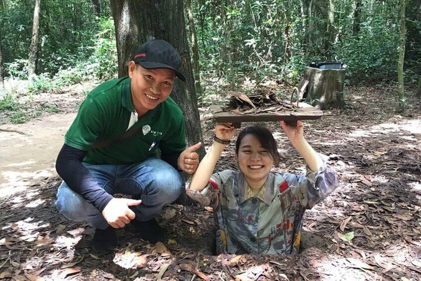 Two people in a forest, one holding a tray with a pot and a pan. 1
