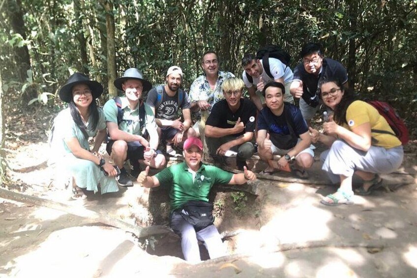 A group of people in a forested area with a mix of trees and sunlight filtering through. 3