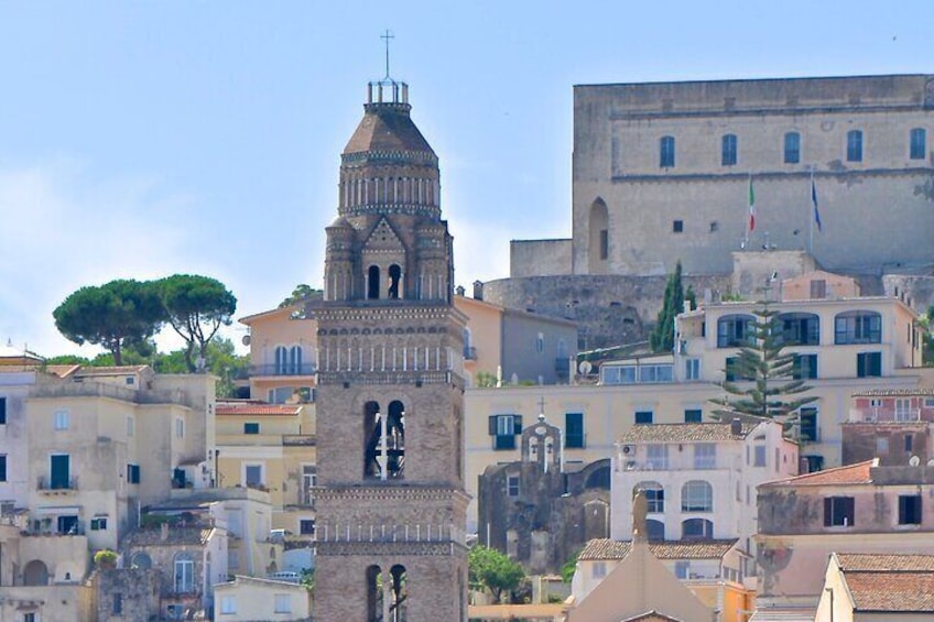 A historic town with a prominent bell tower, a large building with a cross on top, and a flag. 5