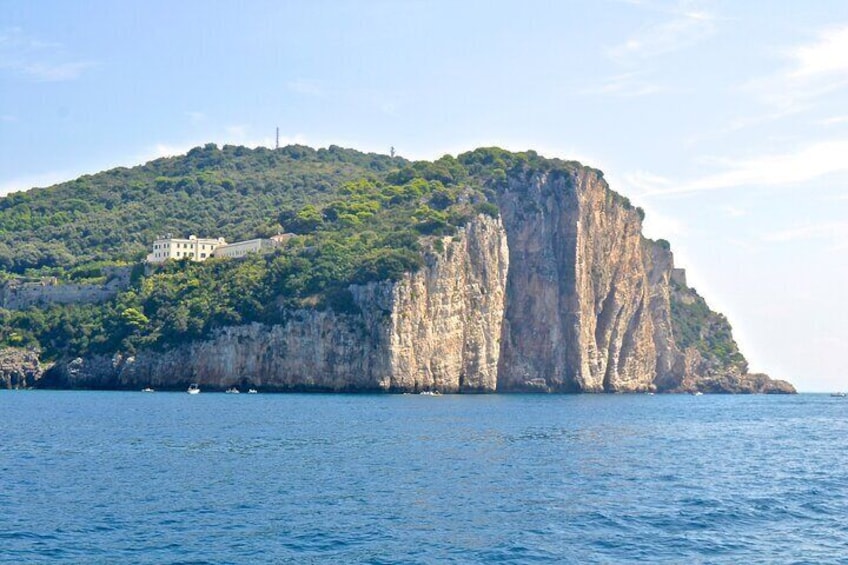 A coastal cliff with a building on top, surrounded by water. 4