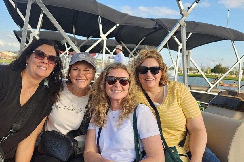 Four people sitting on a boat with a canopy overhead. 4