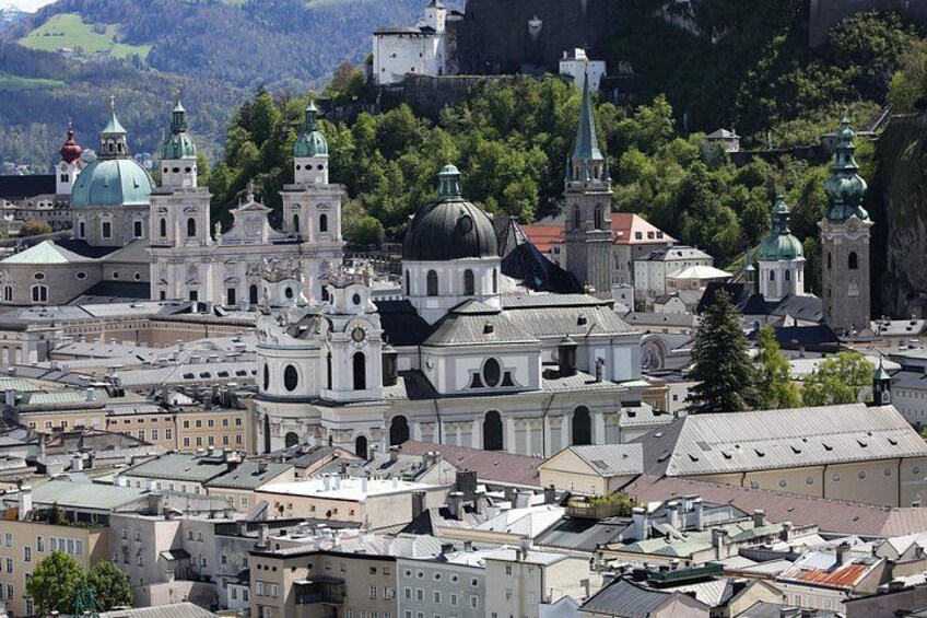 A cityscape with historic architecture, including domed buildings and a castle on a hill. 2