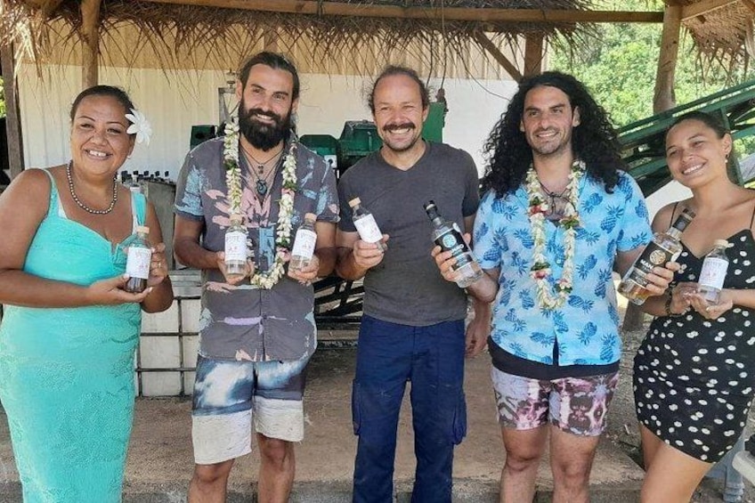 Un grupo de personas sosteniendo botellas, de pie bajo una estructura de techo de paja. 2