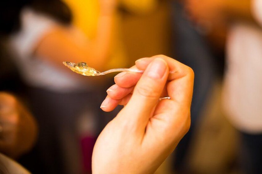 A hand holding a spoon with a clear liquid. 3