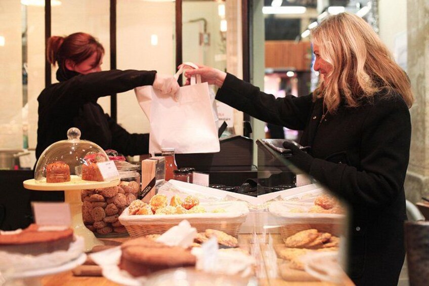 A person at a bakery counter with pastries and a cash register. 2