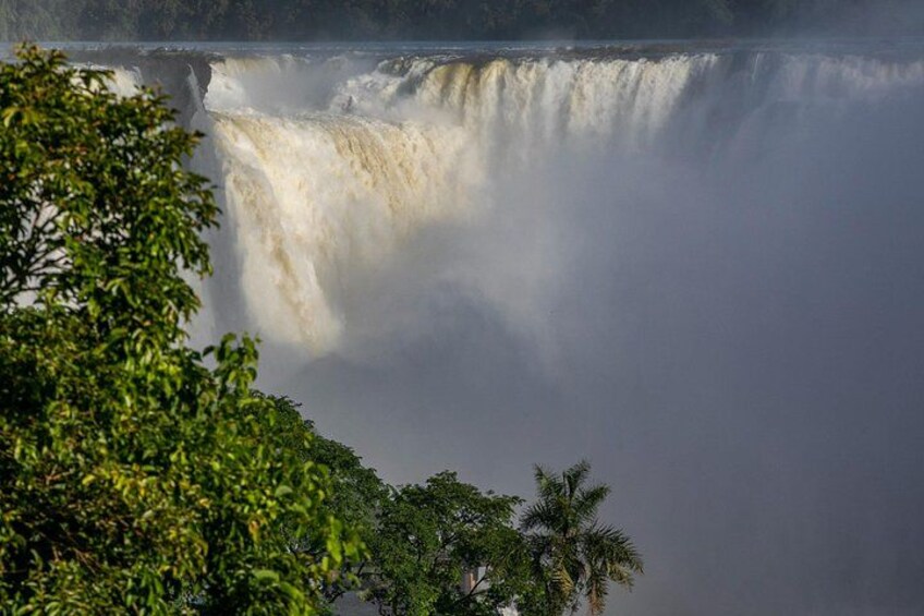 Una cascata che si getta in una pozza avvolta dalla nebbia, circondata da vegetazione lussureggiante. 3
