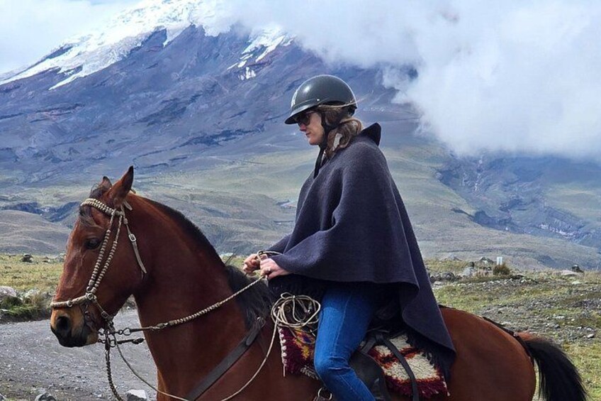 En person rider på en hest på en sti i bjergene, med et sneklædt bjergtop i baggrunden. 4