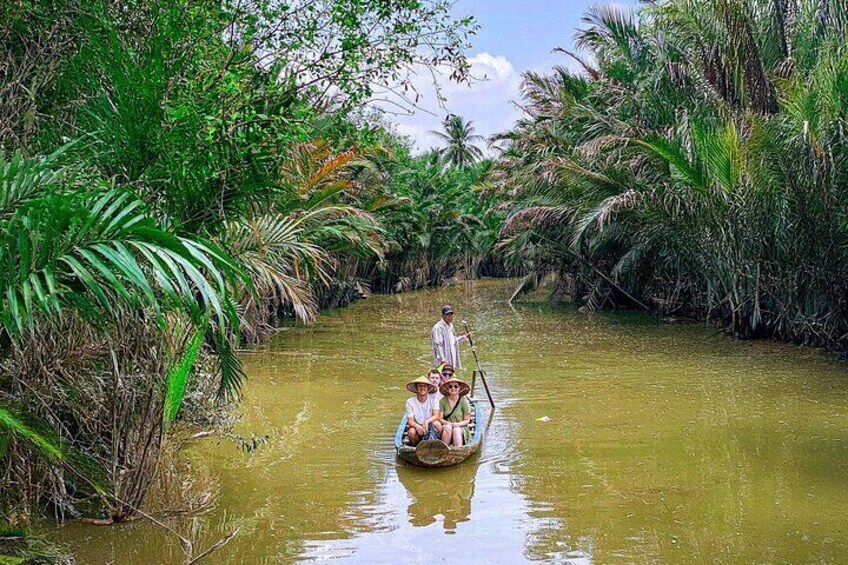 A narrow waterway flanked by dense vegetation and palm trees. 4