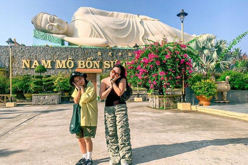 En stor Buddha-staty, en skylt med vietnamesisk text och en person i kamouflagebyxor. 3