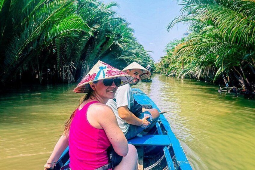 A boat navigating a narrow waterway flanked by dense palm trees. 2