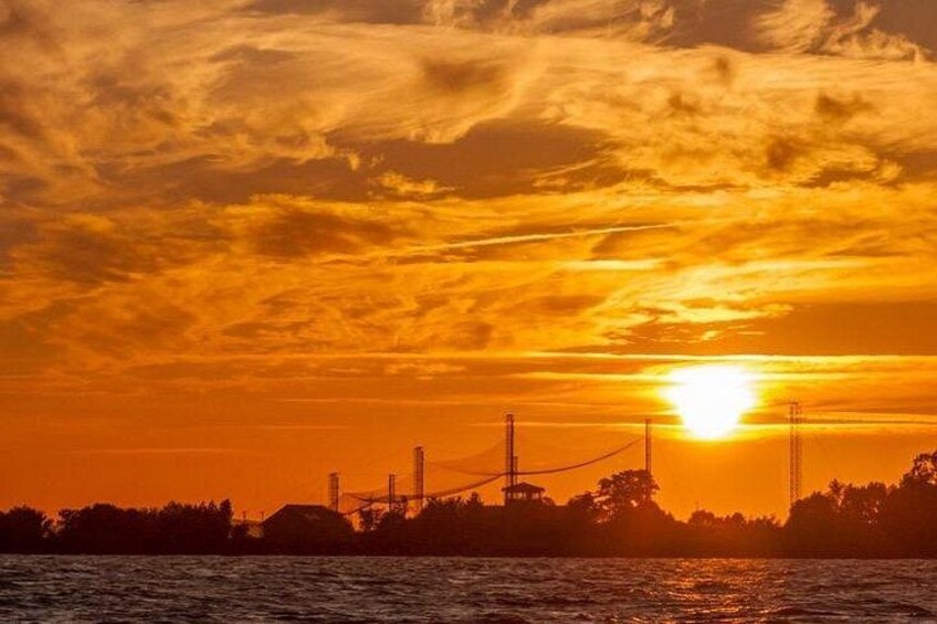 A sunset over a body of water with industrial structures in the background. 4