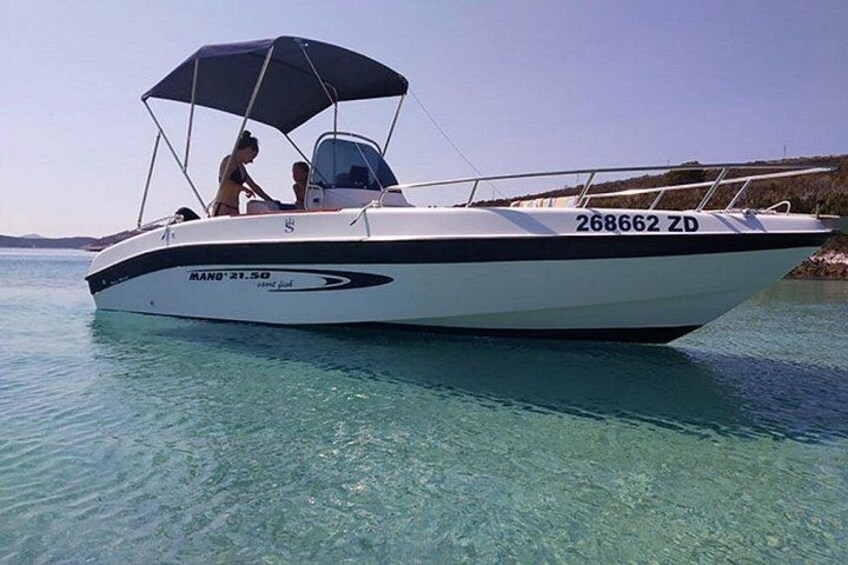 Ein weißes Motorboot mit blauem Verdeck auf klarem, türkisblauem Wasser. Das Kennzeichen lautet 268662 ZD. 1