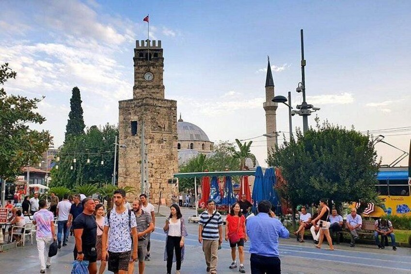 Een levendig plein met een historische toren, een minaret en een koepel op de achtergrond. 5