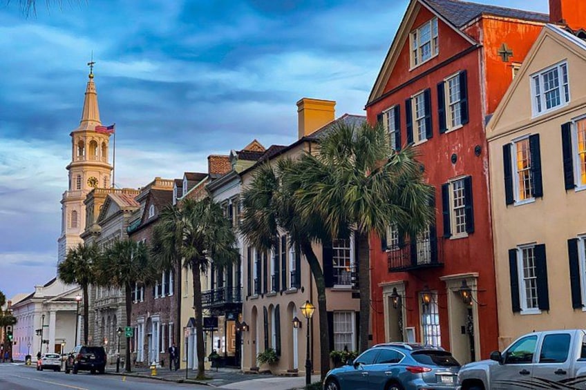 A historic street with colonial architecture, palm trees, and a church steeple. 1