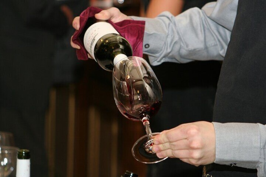 A person pouring wine into a glass. 2