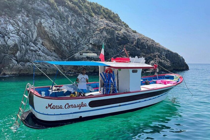 A boat named 'Maria Corsiglia' on calm turquoise waters with rocky cliffs in the background. 4