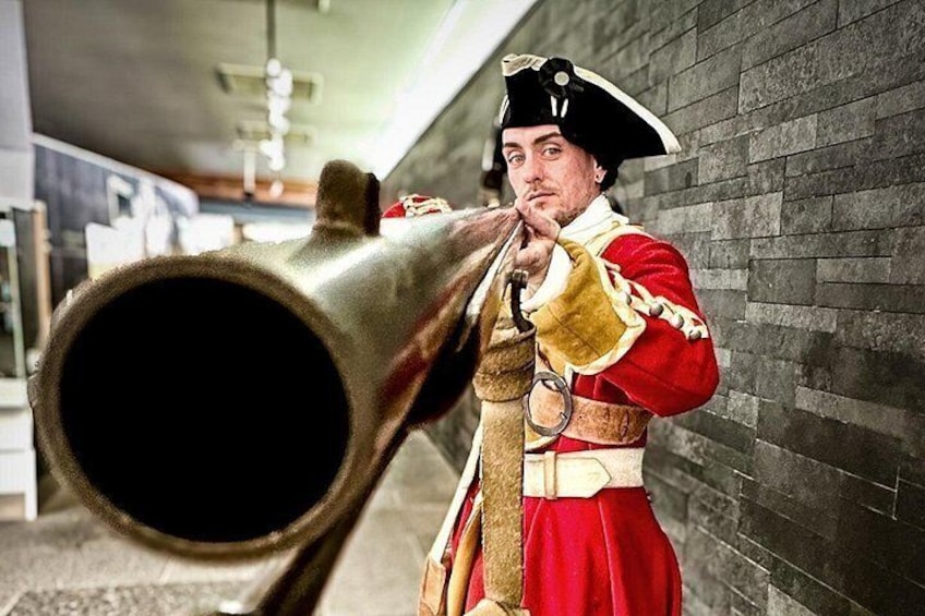 Una persona con uniforme rojo y dorado sostiene un cañón grande. 3