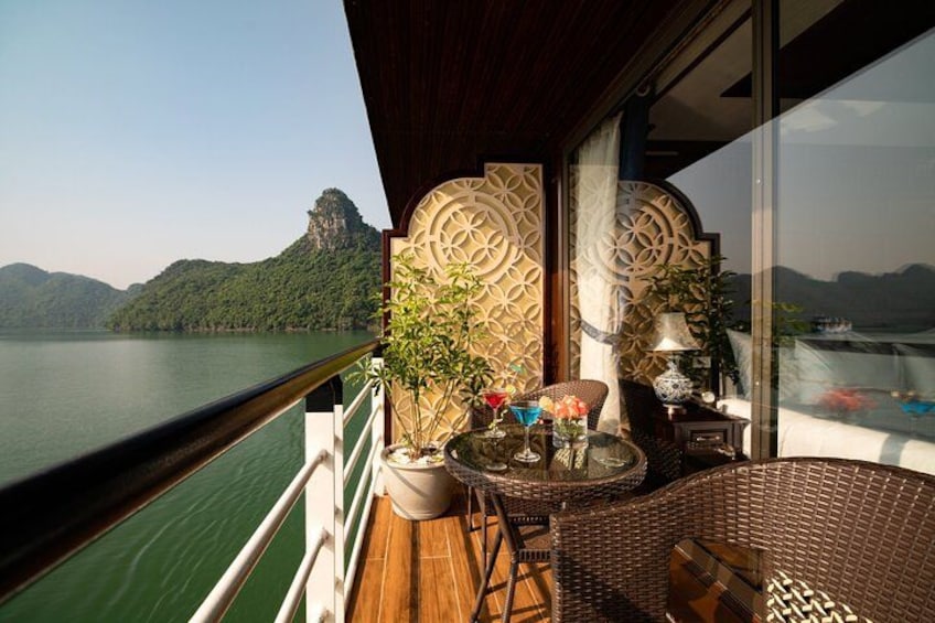A balcony with a view of a lake and mountains, wicker furniture, and decorative wall panels. 2