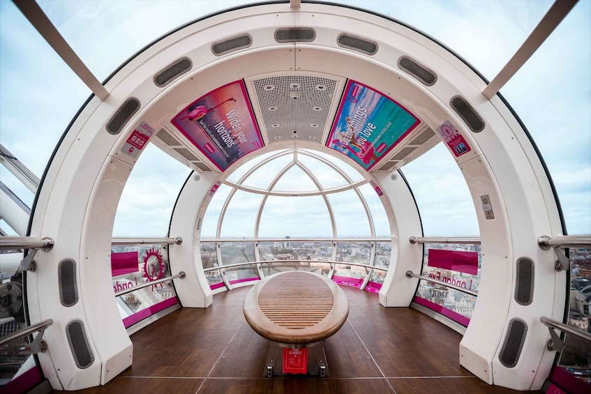 A glass-enclosed observation deck with a wooden bench, city views, and promotional posters. 1