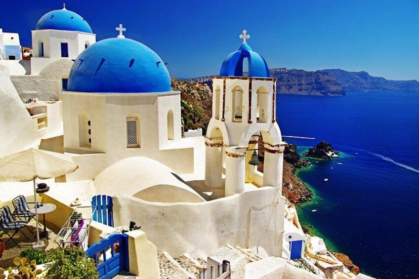 Un pueblo costero con edificios blancos y cúpulas azules, con vistas al mar. 3