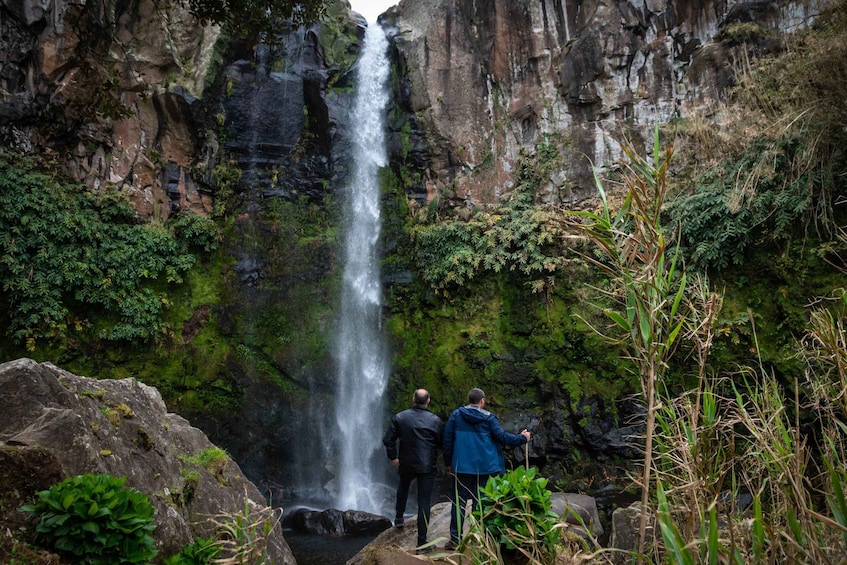 A waterfall in a rocky gorge with two people observing it. 5