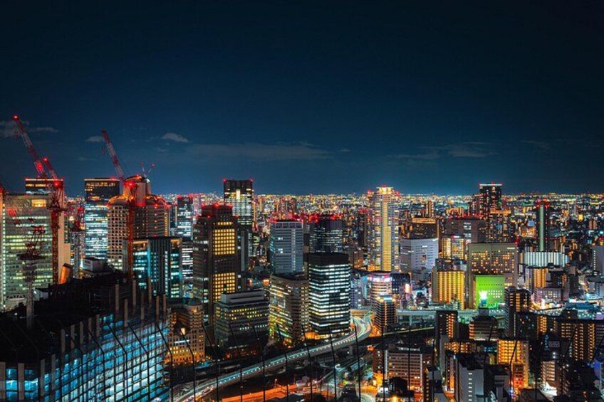 A nighttime cityscape with illuminated buildings and construction cranes. 5