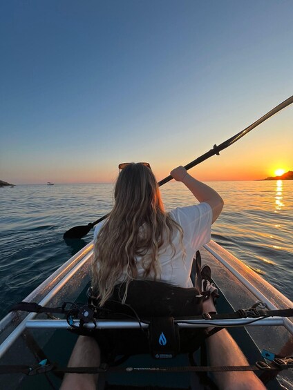 A person in a kayak on calm water during sunset. 1